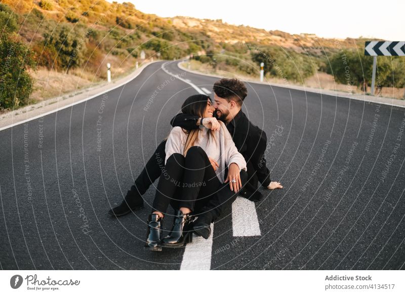 Young couple in love sitting on road embrace gentle together happy young relationship romantic roadway hug adventure trip enjoy romance ethnic affection cuddle