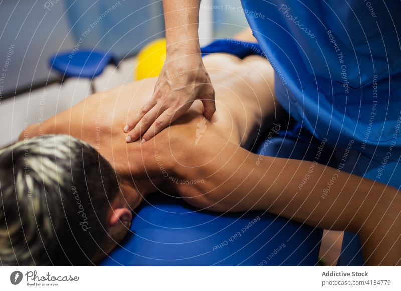 Orthopedist massaging the back of sportsman during medical checkup orthopedist patient recovery examine professional osteopathy aid health care rehabilitation
