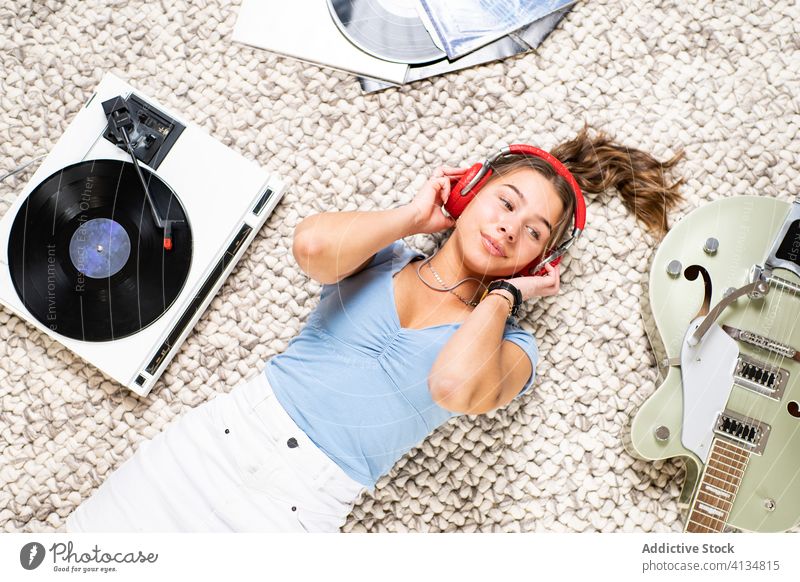 Relaxed woman with headphones listening to music on vinyl record disc home rest chill happy relax smile lying cheerful enjoy player retro meloman young female