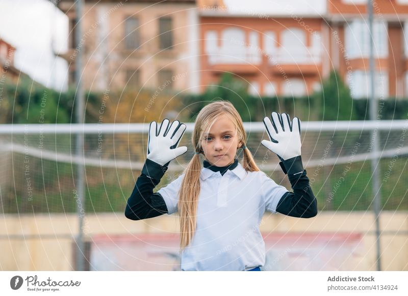 Focused young female goalkeeper waiting ball on green football field in sports club girl soccer player defend training serious stadium match kid uniform game
