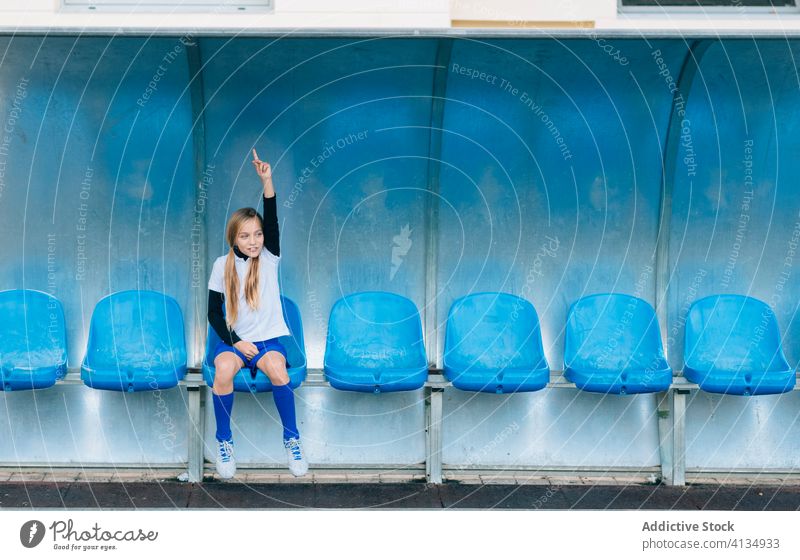 young female player resting on chair at football stadium girl seat soccer decision loose uniform athlete game sport junior sporty result spare jersey tension