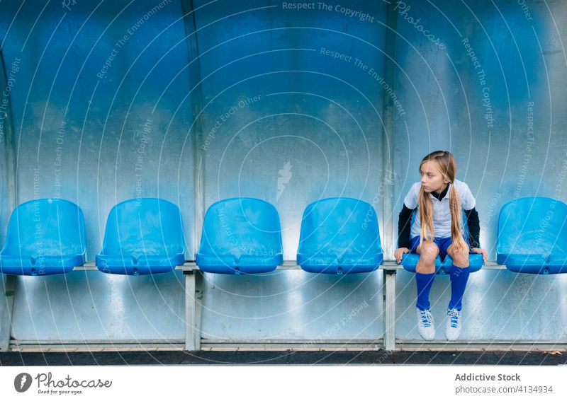 Unhappy disqualified young female player resting on chair at football stadium girl lose frustrate seat failure soccer unhappy dismissal decision loose uniform
