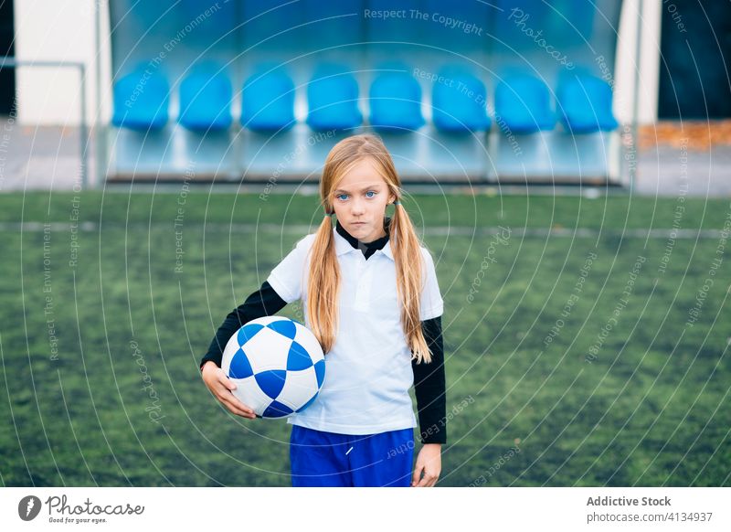 Serious young female player with ball in football arena at sports stadium girl soccer field uniform child kid club childhood athlete equipment preteen