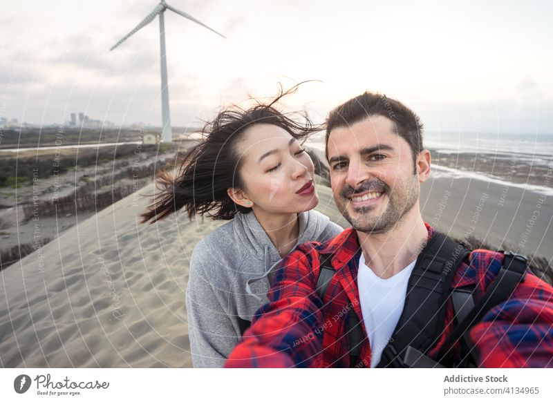 Happy diverse couple embracing and taking selfie on sea beach embrace vacation love relationship travel together bonding girlfriend happy cheerful boyfriend