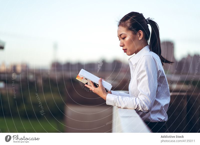 Young busy woman reading book on rooftop businesswoman modern young formal urban break rest asian female ethnic lifestyle smart contemporary intelligent