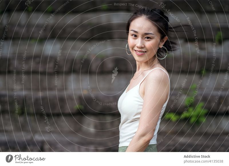 Positive ethnic woman sitting on shabby stairs in park staircase rest happy positive toothy smile casual sporty serene fit stone step style daytime confident