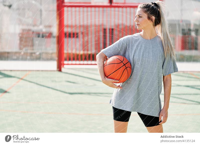 Confident basketball player standing on playground woman confident sport court competitive serious young sportswoman athlete sportswear training activity game