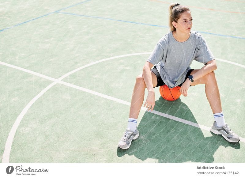 Female basketball player sitting on sports ground woman exercise warm up training prepare court female workout activity game lifestyle wellbeing young power
