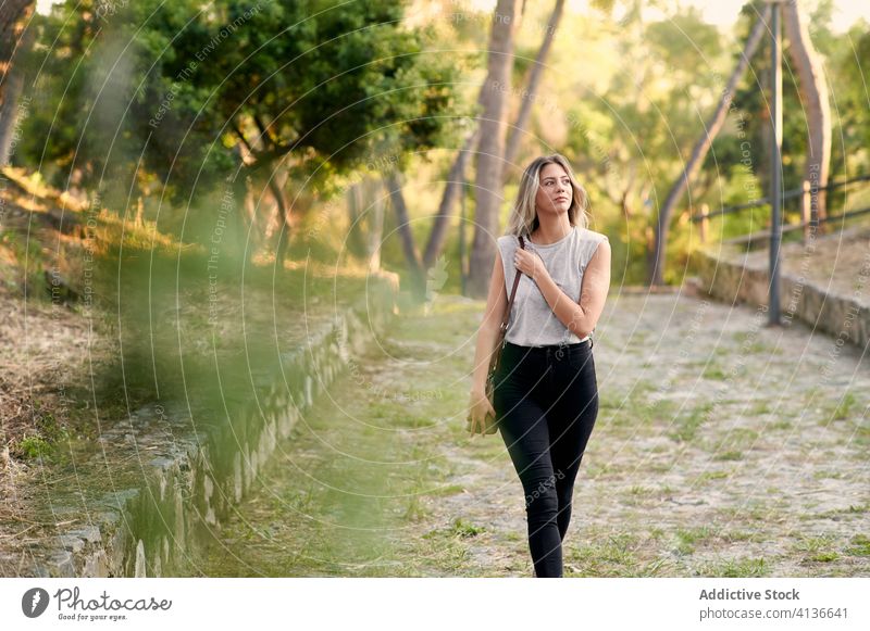 Young woman strolling in green park walk summer calm confident young enjoy relax female pathway lifestyle tranquil nature peaceful trendy carefree harmony