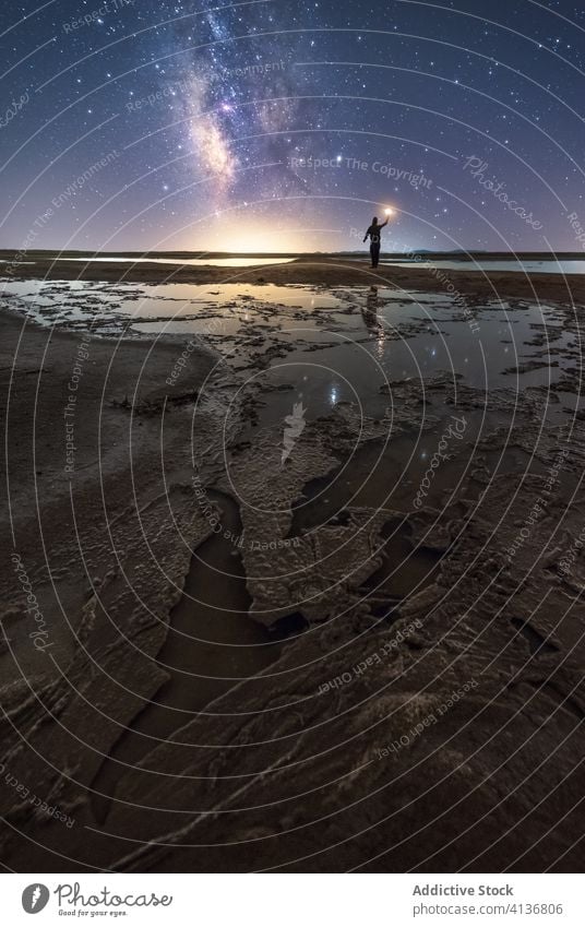 Silhouette of man on lonely shore in starry night nature silhouette reach out sky milky way stand wish catch shooting star coast torch water sea ocean calm