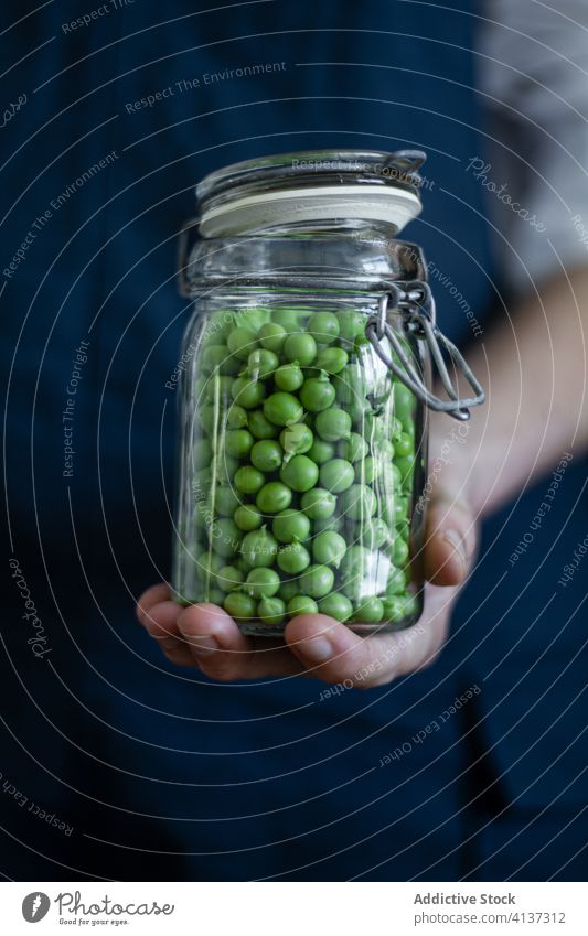 Crop cook with jar of peas green vegetable fresh person glass can organic natural apron food healthy nutrition delicious diet tasty plant meal gourmet vegan