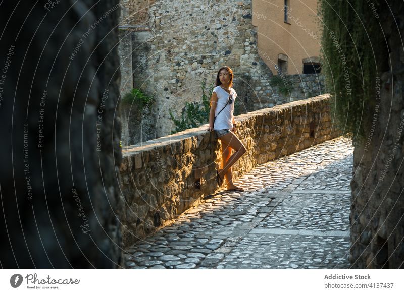 Young woman standing on old stone bridge travel medieval cobblestone building street ancient town spain besalu architecture young ethnic asian female tourism
