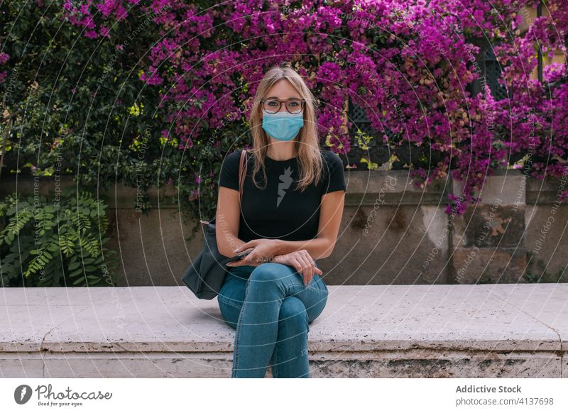 Young woman wearing a face mask outdoors during a pandemic street corona virus protection young city person crisis worried distance sitting girl europa health