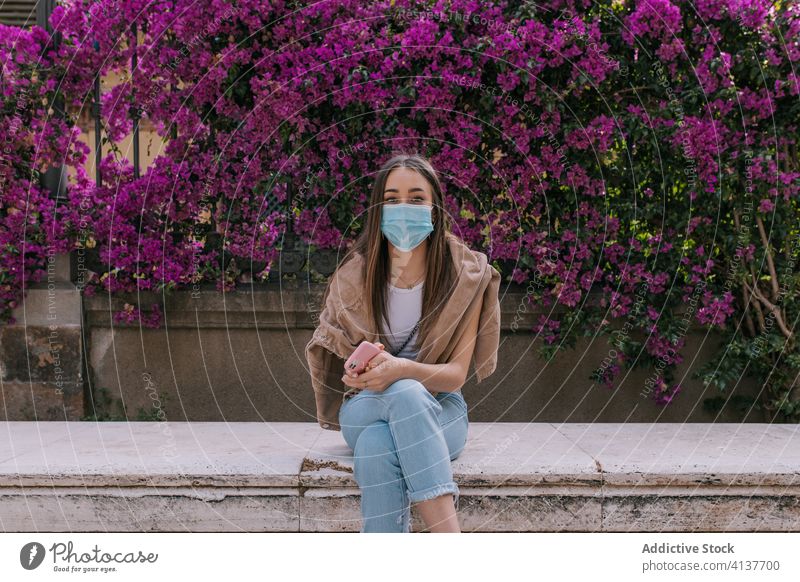 Young woman wearing a face mask outdoors during a pandemic street corona virus protection young city person crisis worried distance sitting girl europa health
