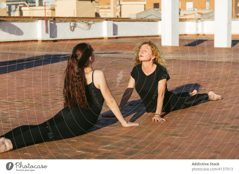 Flexible women practicing yoga back bend asana on terrace together practice pose position cobra bhujangasana prone flexible balance stretch acro yoga partner