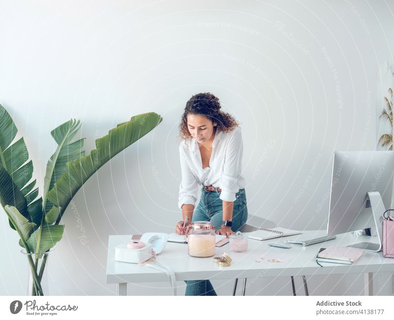 Businesswoman making notes in office writing notebook business smiling work table leaning female palma de mallorca spain style elegant data design decor light
