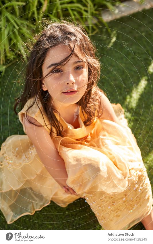 Charming little girl in dress sitting on grass summer smile adorable kid rest portrait childhood calm happy tranquil cute charming princess peaceful innocent