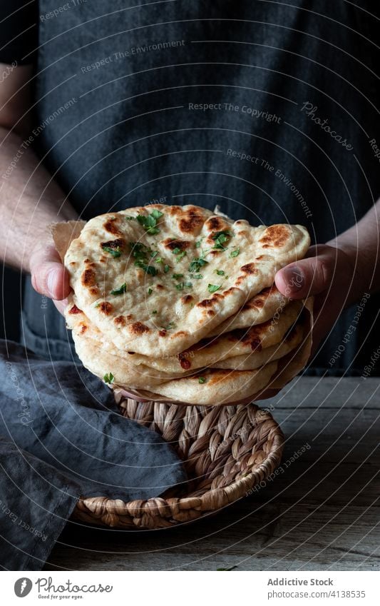 Male cook with Naan bread at table naan bread baker tradition man fresh baked bakery herb male apron indian food cuisine gourmet chef delicious culinary meal