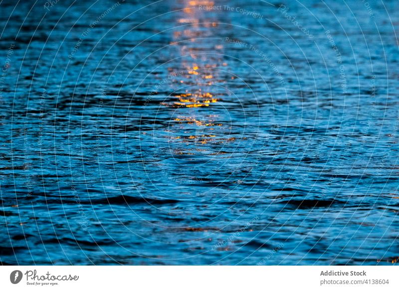 Light reflected in dark water light reflection ripple texture sunset dusk background nature night glow shiny illuminate abstract bright beam surface colorful