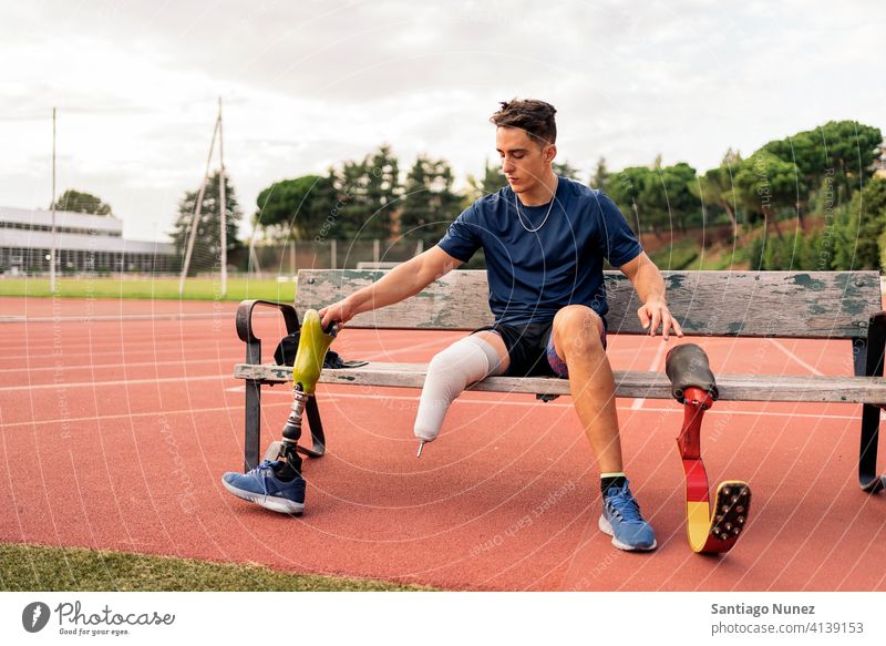Disabled Man Athlete Sitting in a Bench putting changing leg prosthesis sitting bench portrait boy running track stadium athlete young man runner sport