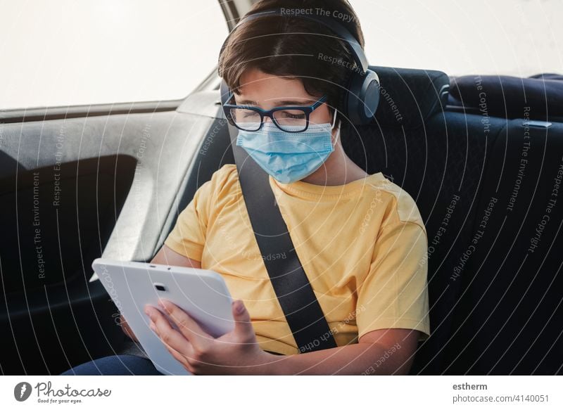 kid with medical mask riding in a car coronavirus tablet motor vehicle seatbelts security safety epidemic pandemic quarantine child family covid-19 trip travel