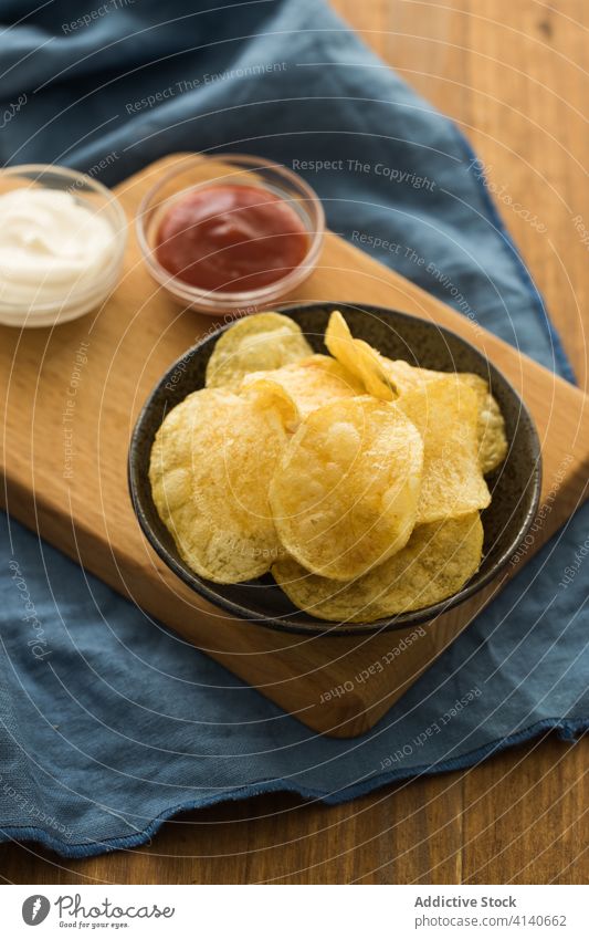 Tasty potato chips in bowl on table crispy tasty ketchup sour cream junk food snack yummy fast food delicious sauce appetizer meal appetizing gastronomy