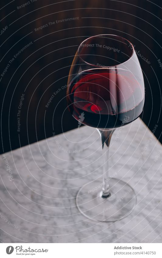 Glass of red wine on table wineglass alcohol beverage crystal glassware drink delicious marble fresh tasty liquid taste palatable delectable serve refreshment