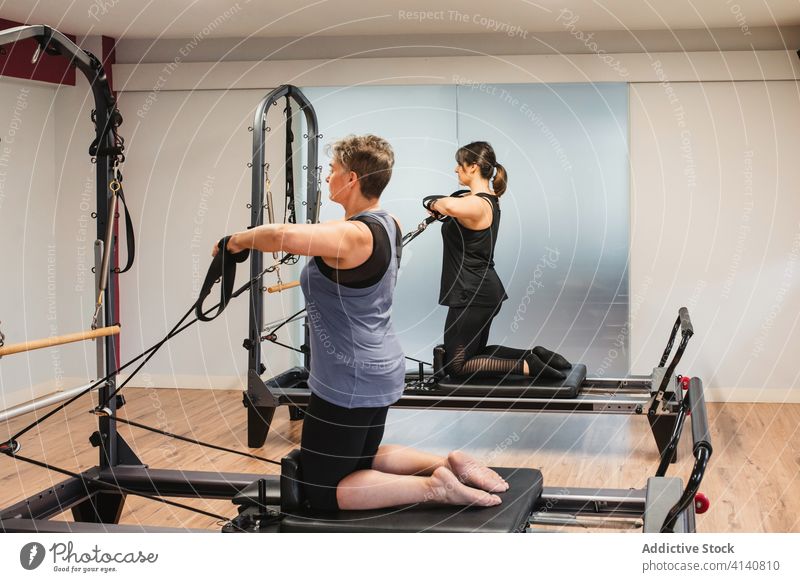Sporty women during training on pilates reformers sportswomen machine exercise together sporty resist activity activewear metal equipment workout athlete
