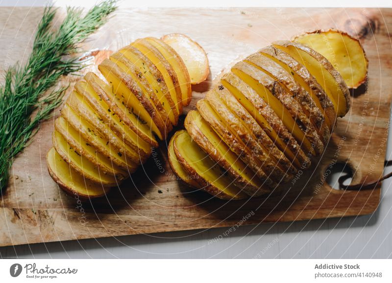 Hasselback potatoes on wooden cutting board in kitchen hasselback potato baked serve dish dill delicious dinner homemade tasty sprig meal food cuisine nutrition