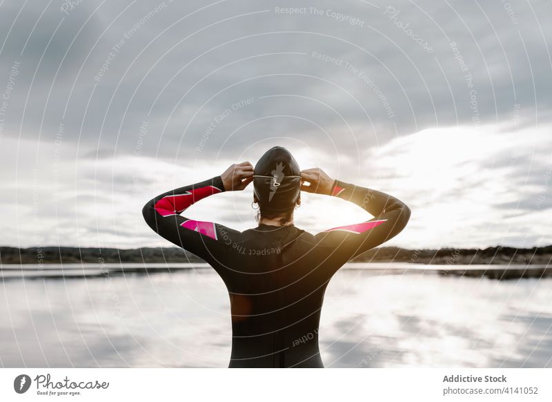 Anonymous woman in wetsuit wearing glasses on lake of shore diver goggles swimsuit extreme environment swimmer aqua sporty travel determine sportswoman vitality