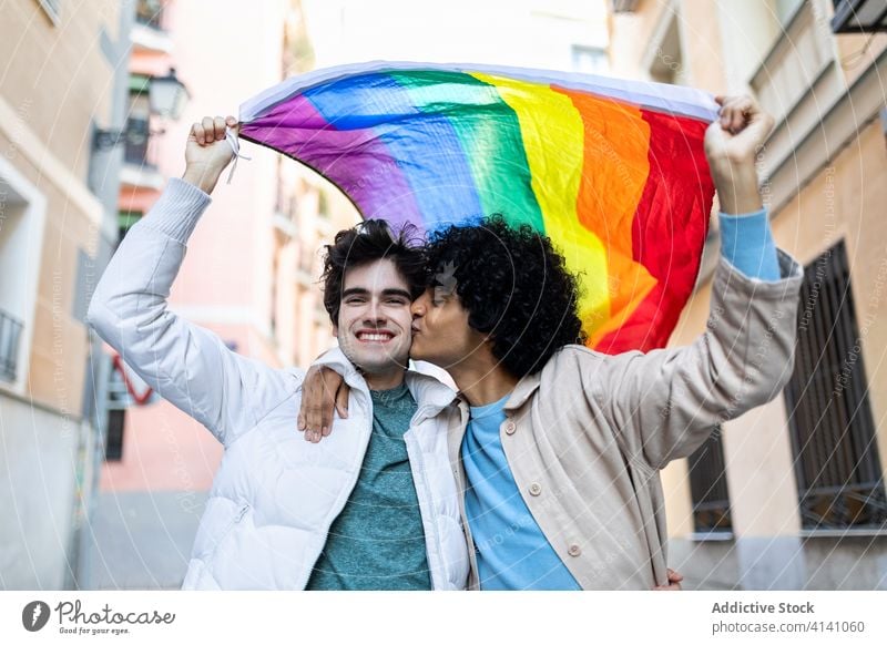 Loving gay couple with LGBT flag lgbt kiss street tolerance relationship homosexual rainbow diverse multiracial ethnic affection love freedom romantic content