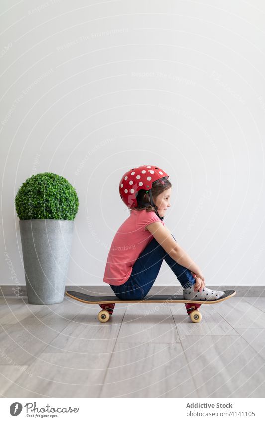 Happy preteen girl riding skateboard at home game entertain fun child play decor longboard helmet kid dream stay at home having fun safety social distancing