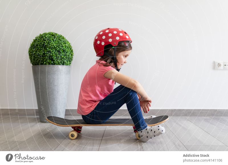 Happy preteen girl riding skateboard at home game entertain fun child play decor longboard helmet kid dream stay at home having fun safety social distancing