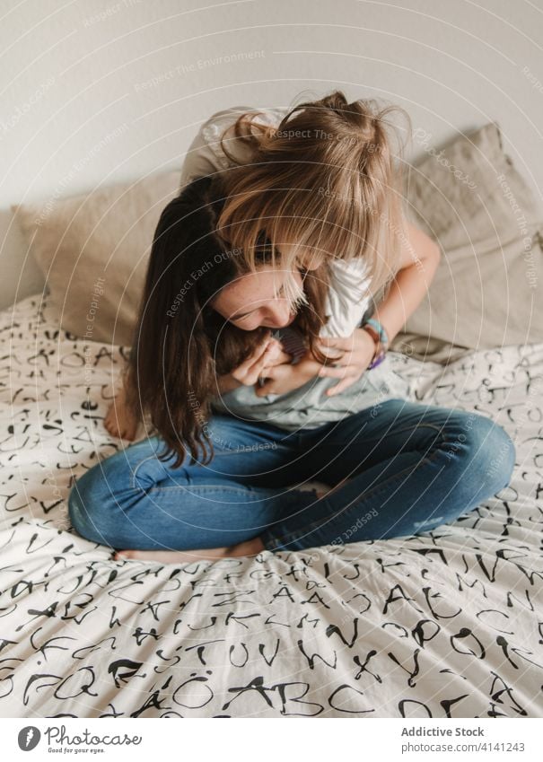 Teenage girl tickling little sister on bed tickle laugh play playful having fun game weekend together cheerful home teen happy cozy joy sibling relative