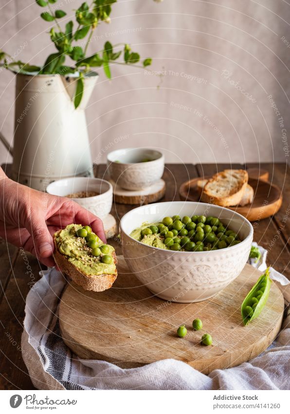 Unrecognizable person eating bread with hummus pea food hand green natural tasty appetizer starter serve cook fresh nutrition healthy delicious cuisine toast