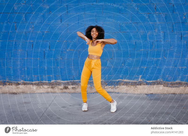 Cheerful African American woman with afro hairstyle in dancing pose dance move vivid vibrant cheerful smile motion color female black ethnic african american