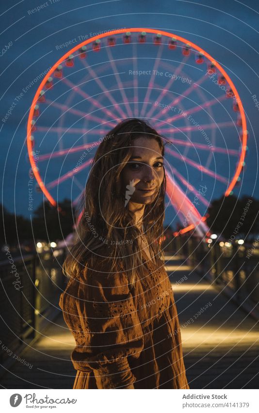 Woman on night promenade with Ferris wheel woman pier ferris wheel glow illuminate fairground carousel sightseeing montreal canada holiday vacation evening