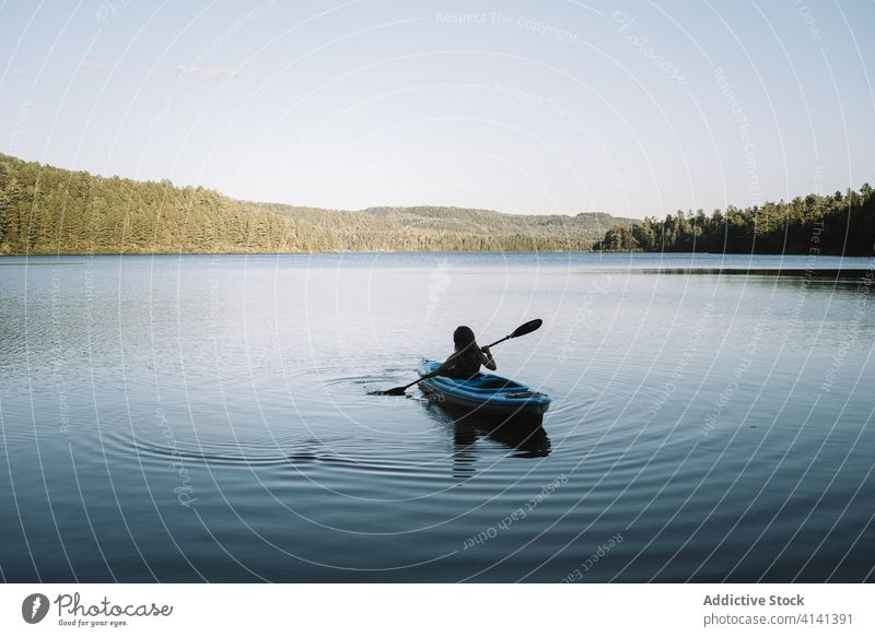 Unrecognizable woman rowing boat on river kayak travel oar silhouette cloudless national park la mauricie quebec canada trip calm lake serene tranquil rest