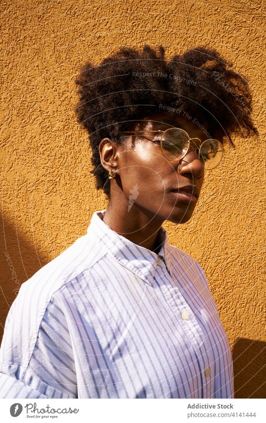Stylish pensive black woman on street in sunny day personality trendy colorful afro tranquil thoughtful glasses calm brunette female slim slender fashion