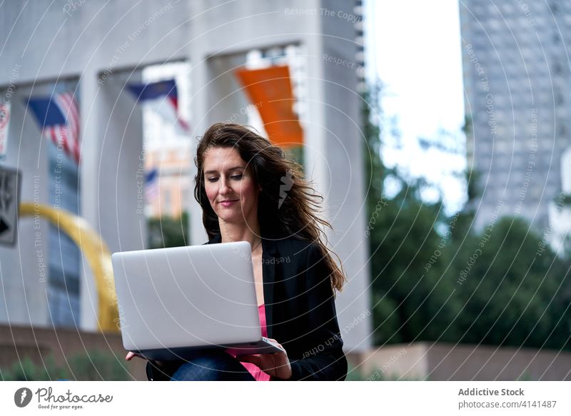 Businesswoman with laptop on city street entrepreneur businesswoman confident cityscape formal well dressed professional female cheerful content smile determine