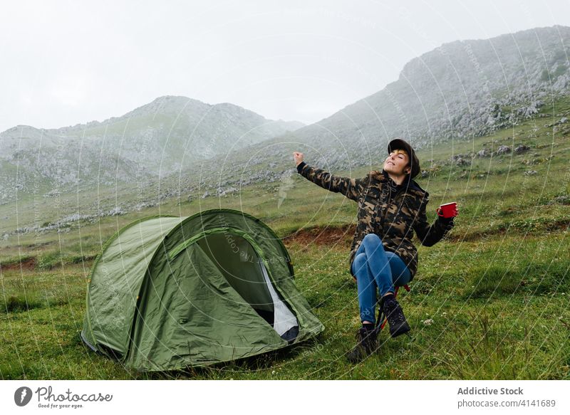 Woman in outerwear stretching body near camping tent in nature woman highland content relax traveler morning wanderlust freedom landscape harmony joy casual