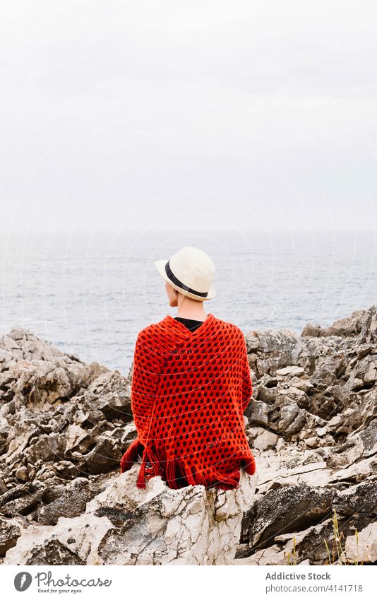 Stylish female tourist enjoying seascape from rocky cliff woman sit coast travel admire nature freedom relax jesters of arenillas spain asturias llanes style