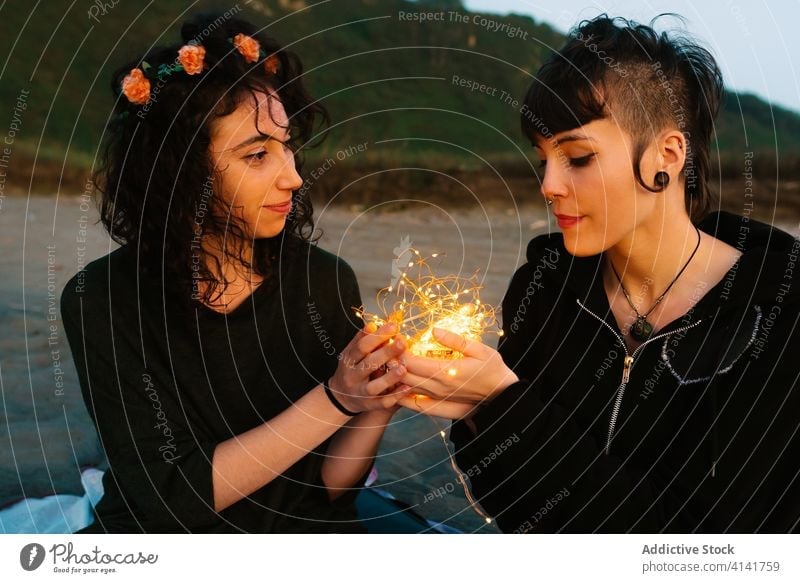 Loving lesbian couple with glowing garland on beach girlfriend illuminate touch love lgbt homosexual gentle affection rest relationship romantic relax tender