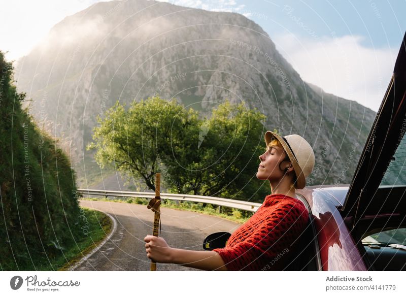 Tranquil woman near car in mountains carefree traveler highland road enjoy spectacular scenery female vacation nature transport adventure freedom trip vehicle