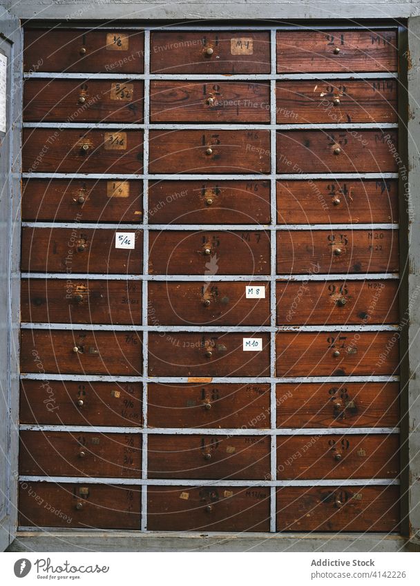Many horizontal wooden drawers with dents on surface in studio archive texture background handle number geometry symmetry similar workshop many blot wavy line