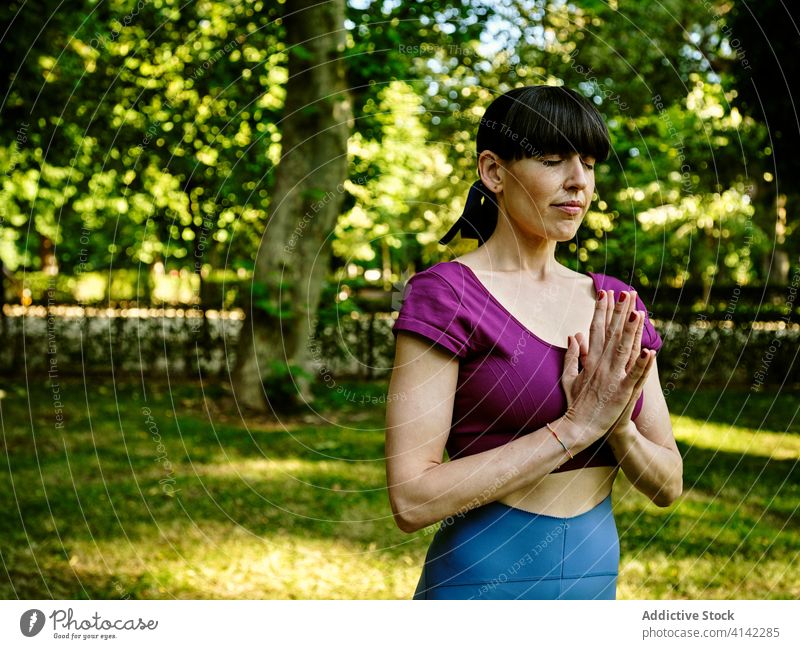 Woman doing yoga in Mountain pose woman mountain pose tadasana namaste relax prayer hands eyes closed practice tranquil healthy meditate park harmony calm