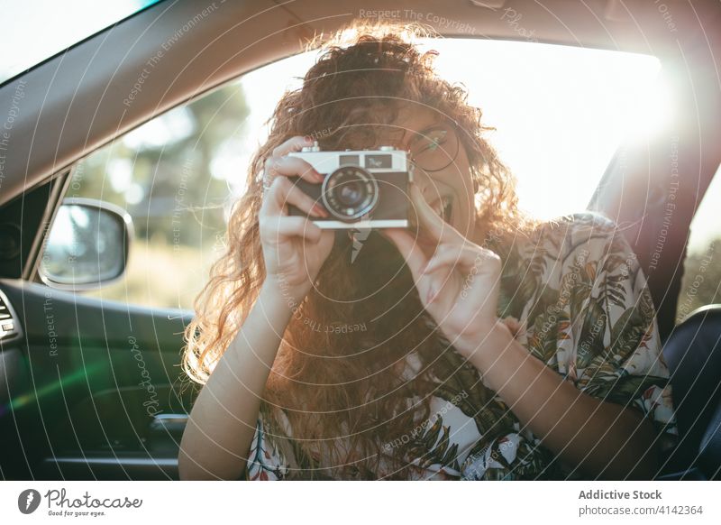 Happy woman taking photo on camera from inside car take photo photo camera digital moment eyes closed sunshine cheerful using device hobby toothy smile happy