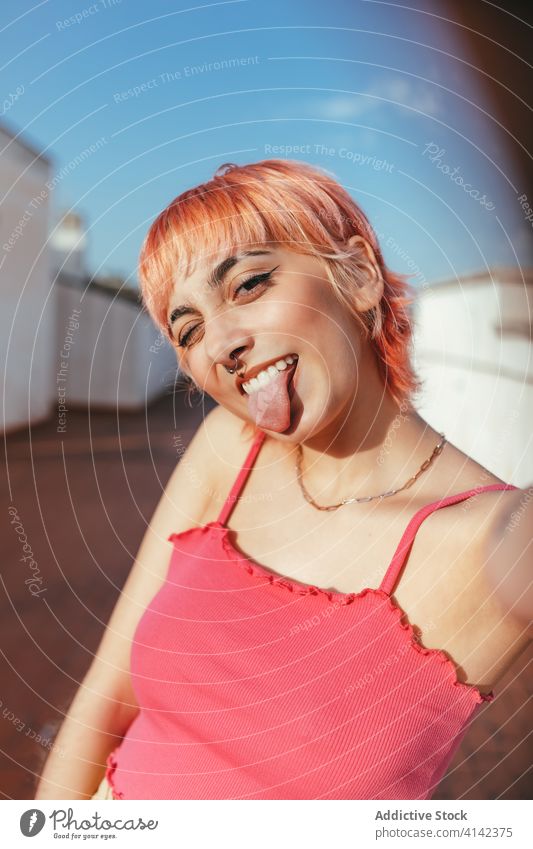 Young woman with pink hair in city millennial make face carefree different behavior expressive cityscape grimace female creative modern trendy gesture style fun