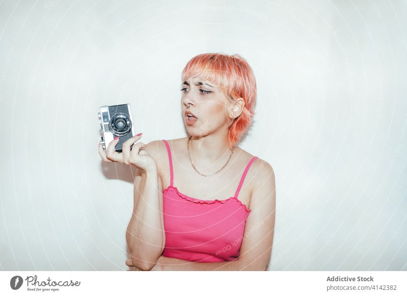 Rebellious woman taking photos on retro camera millennial rebel take photo photographer naughty vintage female piercing pink hair style photography grimace