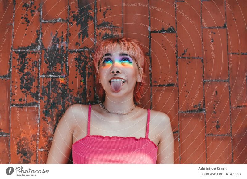 Naughty woman with tongue out in city millennial naughty show tongue pink hair make face carefree rainbow behavior expressive female grimace different creative